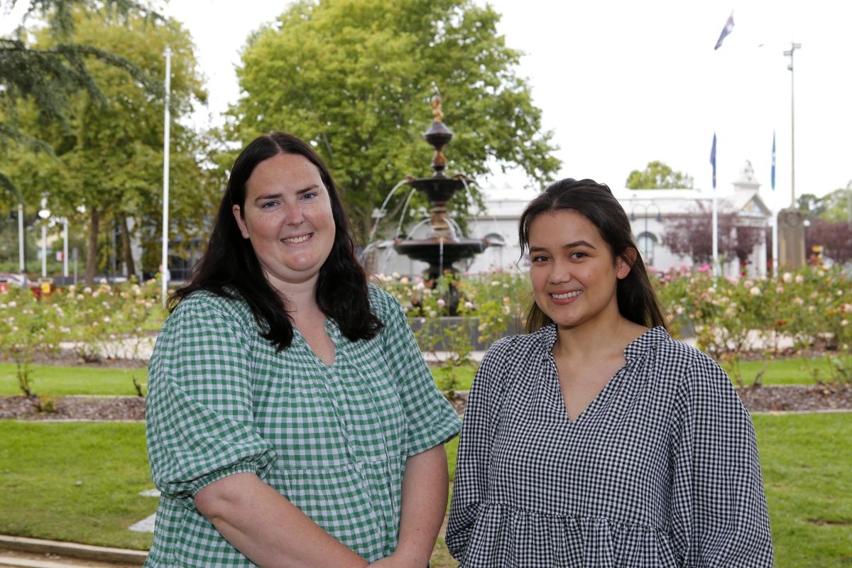 Two women in foreground, fountain and council chambers in background