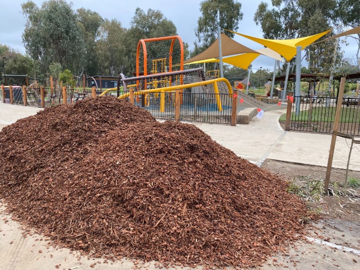 A large heap of mulch beside a playground