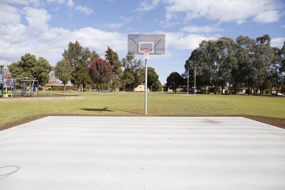 A half basketball court in a park. 