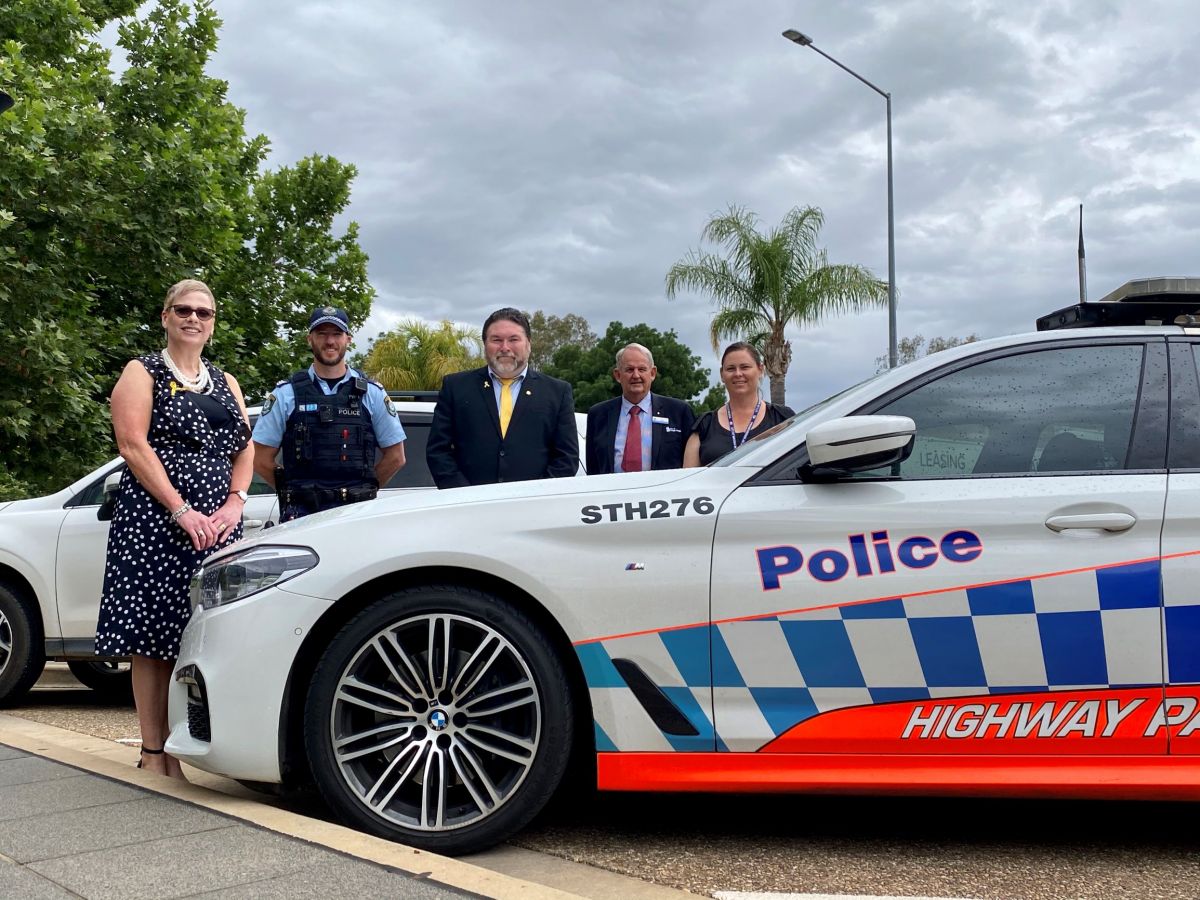 A group of people standing behind a highway patrol car