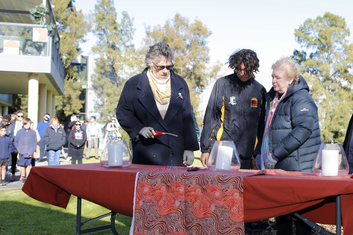 Two Wiradjuri Elders with school student lighting candles at National Sorry Day ceremony