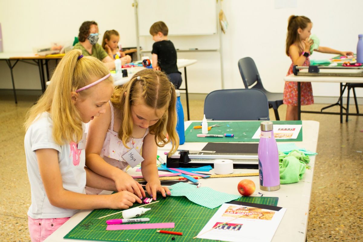 Two young girls in foreground working with art & craft material on table