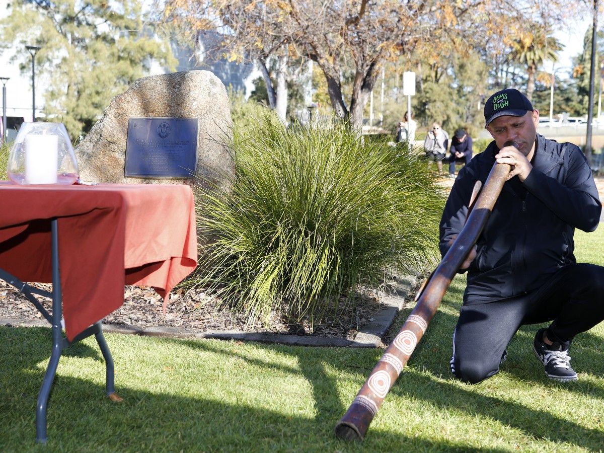 Man playing didgeridoo at National Sorry Day ceremony