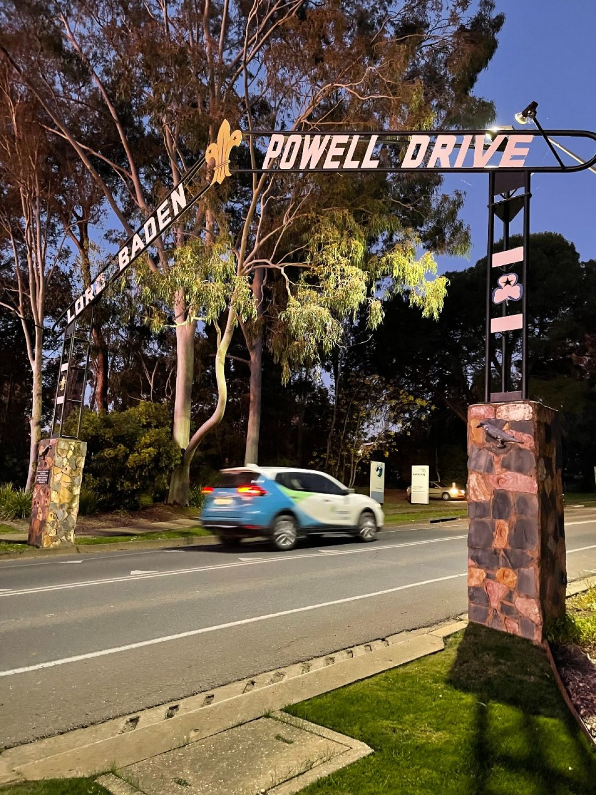 Car driving under the Lord Baden Powell Drive sign in early evening