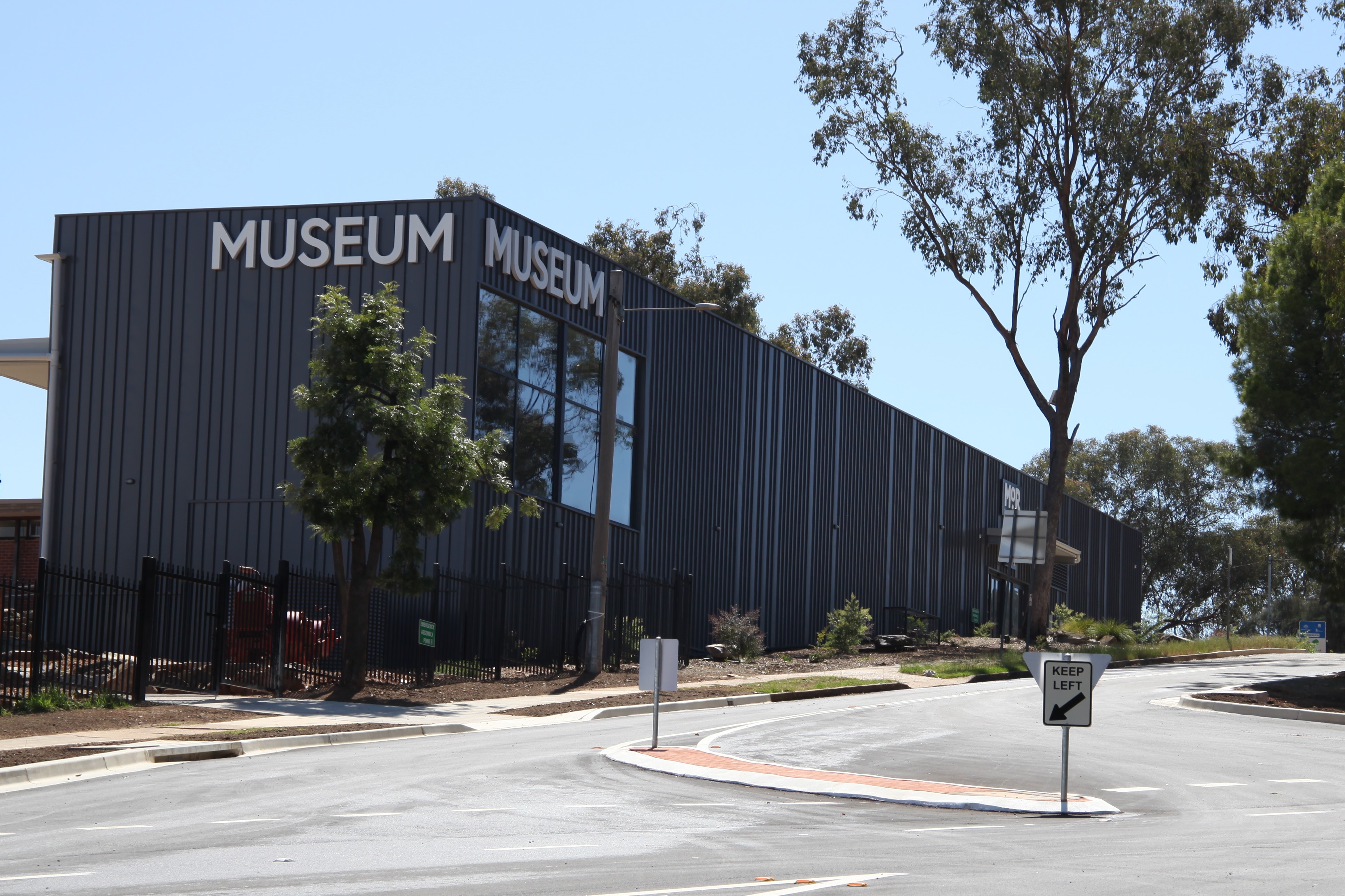 A large grey building at the top of a hill with the word museum on the facades. 