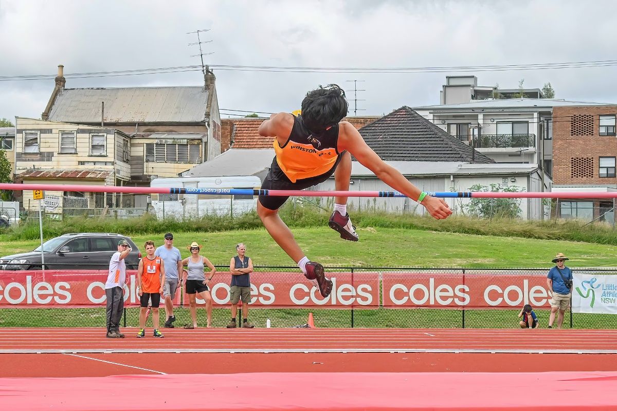 Rear view of male teenage athlete in high jump