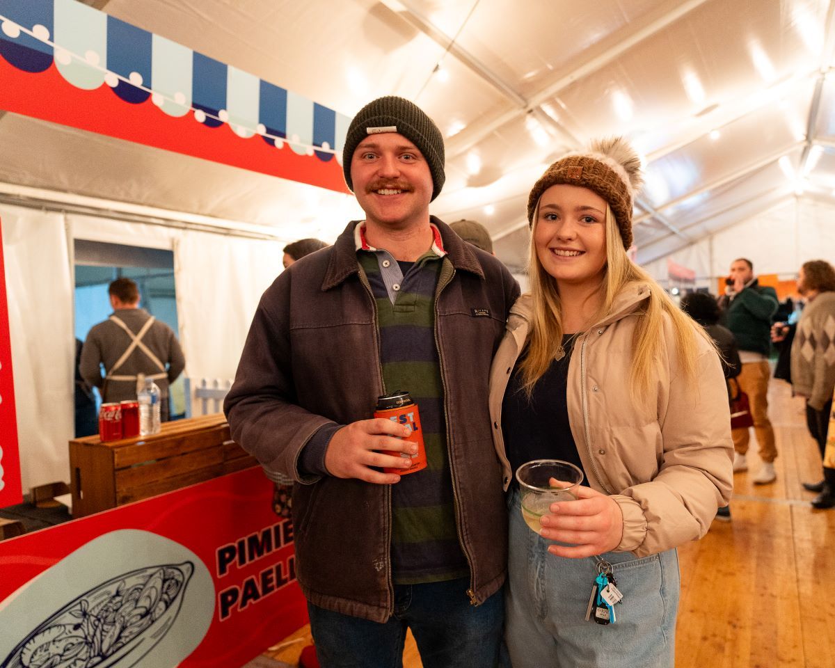 A man and a woman standing in a marque having beverages. 