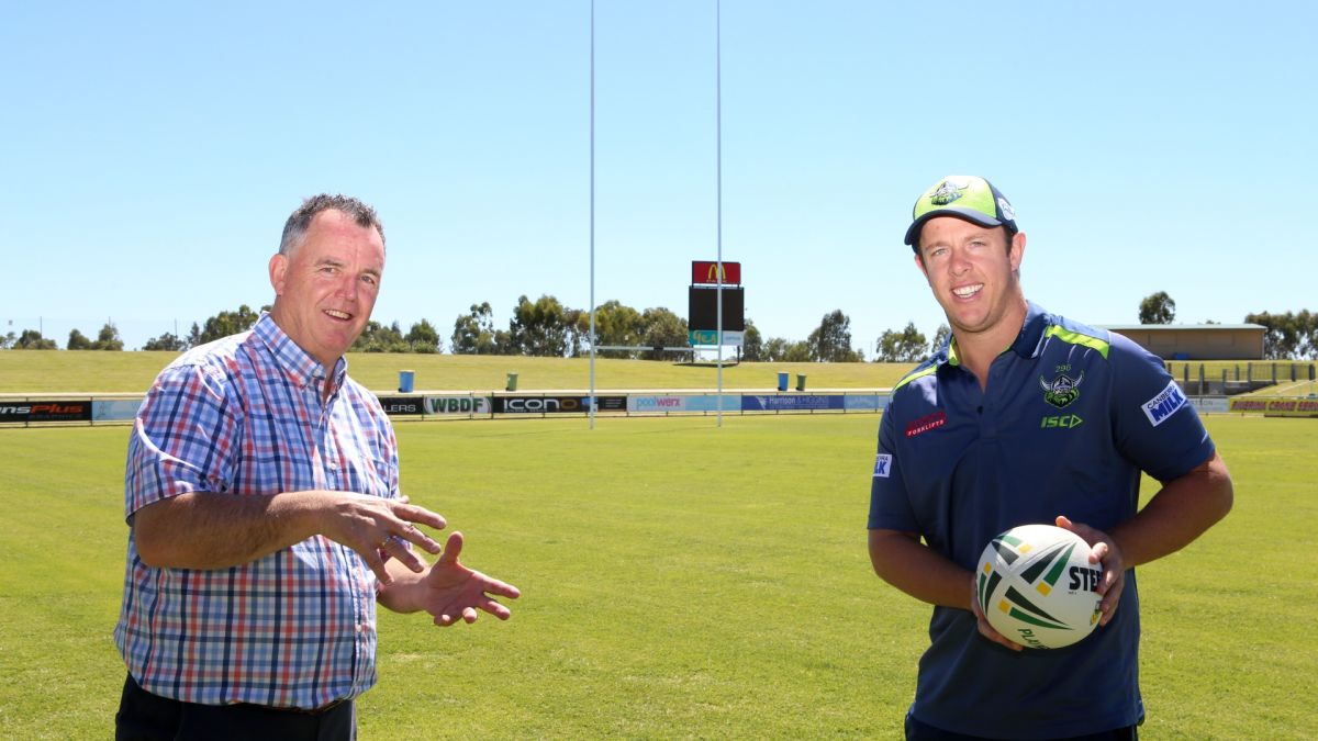 Two men, one holding football, standing on Rugby League pitch