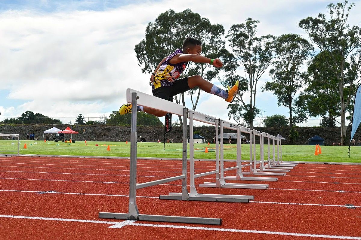 Side view of young male athlete hurdling