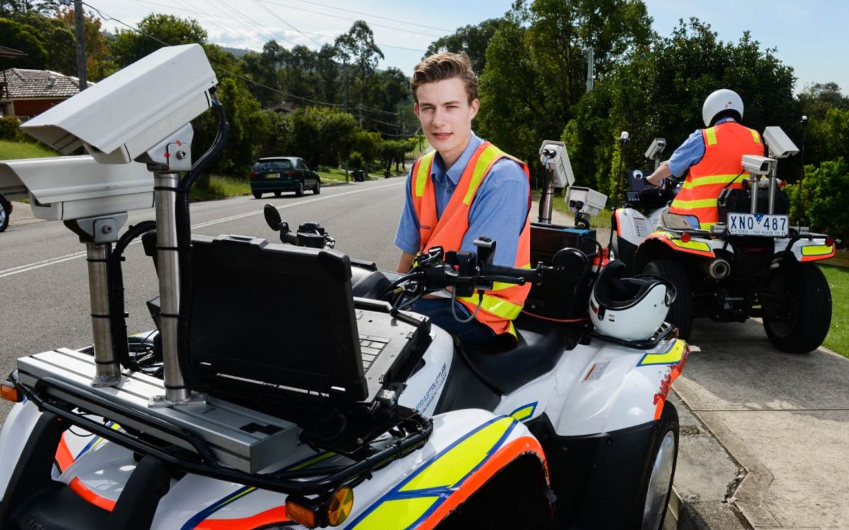 A man sitting on a modified quadbike that is used to assess footpath conditions. Another man is riding away on a similar quadbike in the background. 