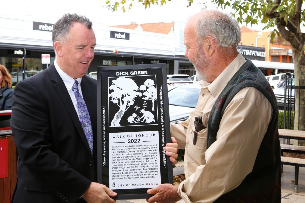 Two men holding framed picture of Walk of Honour plaque