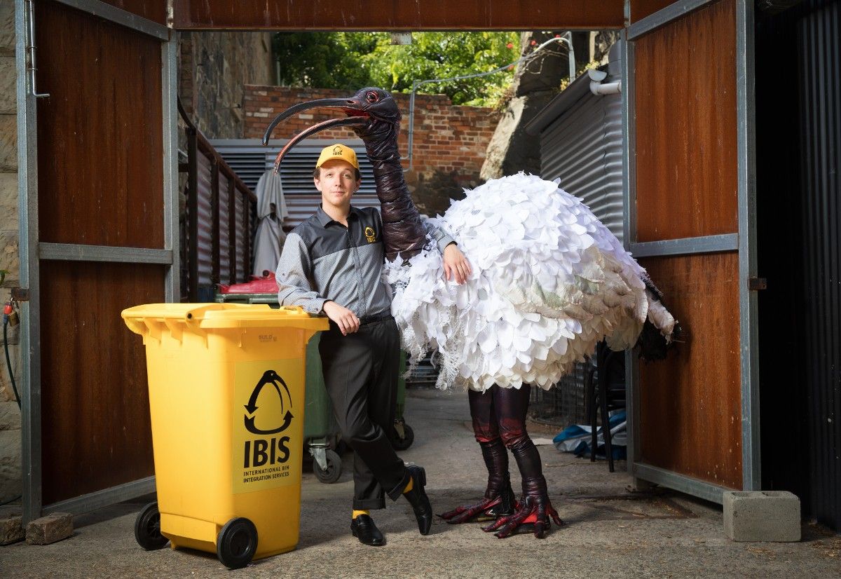 Man standing next to yellow recycling bin and man dressed as an ibis