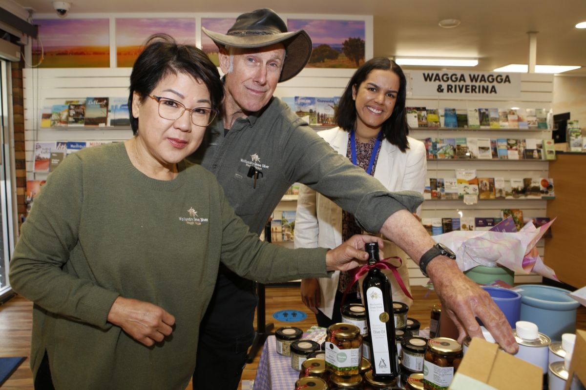 Husband and wife olive producers and council staff inside Wagga Visitor Information Centre with products in foreground