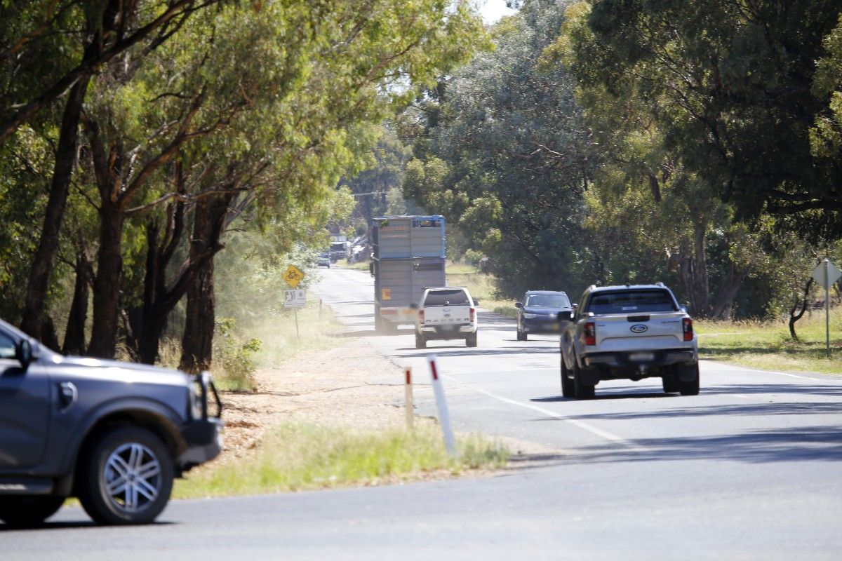 Vehicles on Mitchell Road, include a livestock truck in the distance