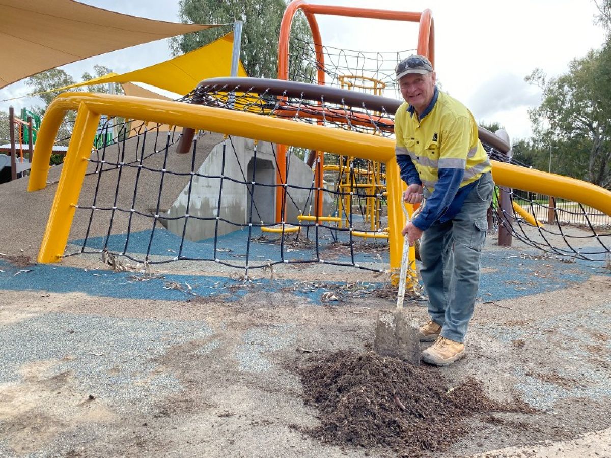 A man shoveling mud from a playground